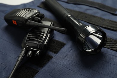 Photo of Flashlight and walkie talkies on bulletproof vest, closeup. Police equipment