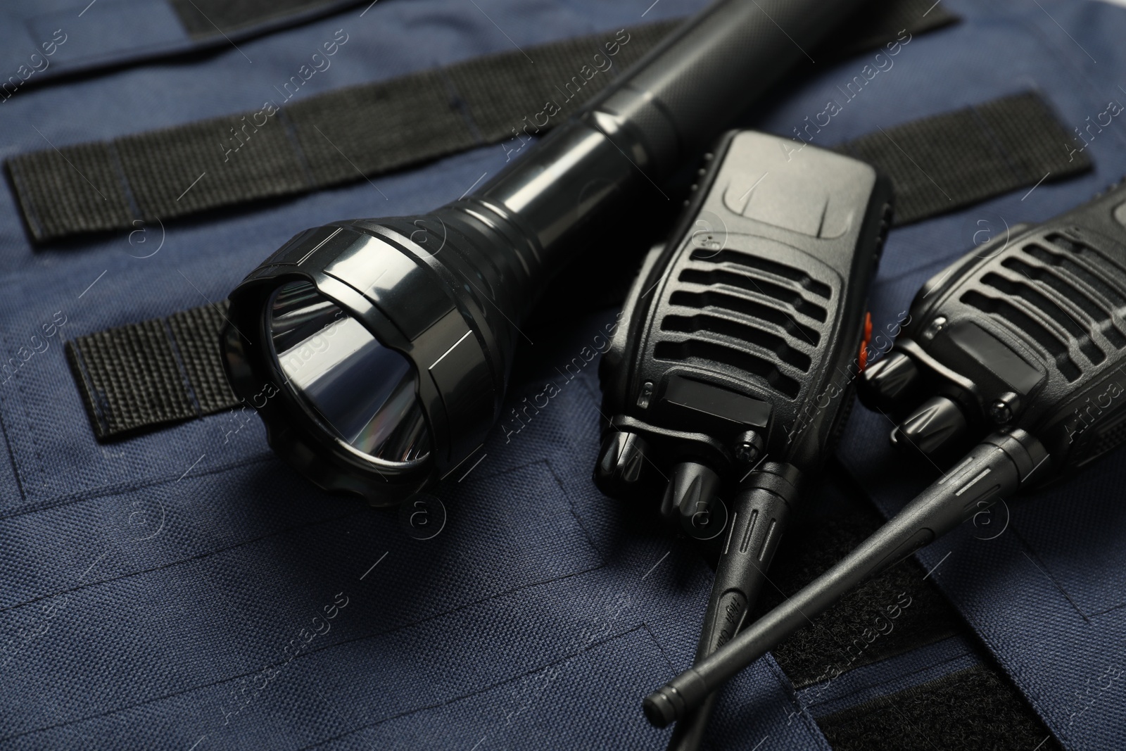 Flashlight and walkie talkies on bulletproof vest, closeup. Police equipment Photo of Flashlight and walkie talkies on bulletproof vest, closeup. Police equipment