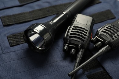 Photo of Flashlight and walkie talkies on bulletproof vest, closeup. Police equipment