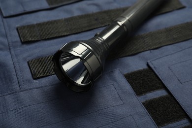 Photo of Flashlight on bulletproof vest, closeup. Police equipment