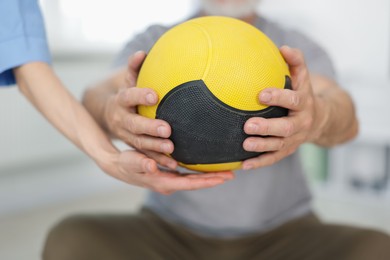 Photo of Doctor and patient exercising with medicine ball in clinic, closeup