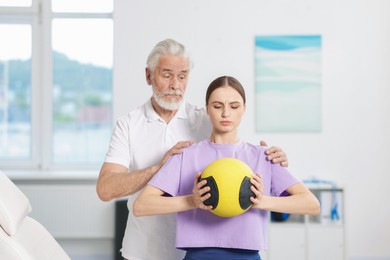 Photo of Doctor and patient exercising with medicine ball in clinic