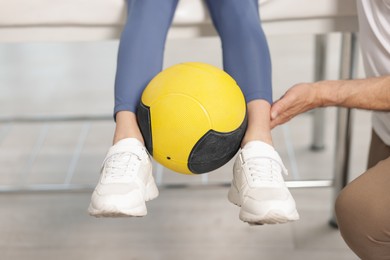 Photo of Doctor and patient exercising with medicine ball in clinic, closeup