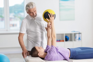 Photo of Doctor and patient exercising with medicine ball in clinic