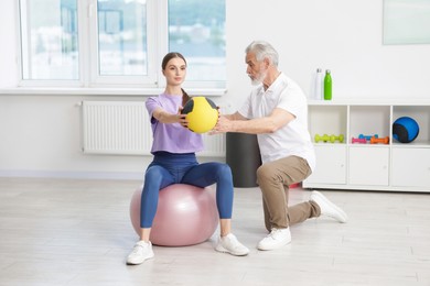 Photo of Doctor and patient exercising with medicine ball in clinic