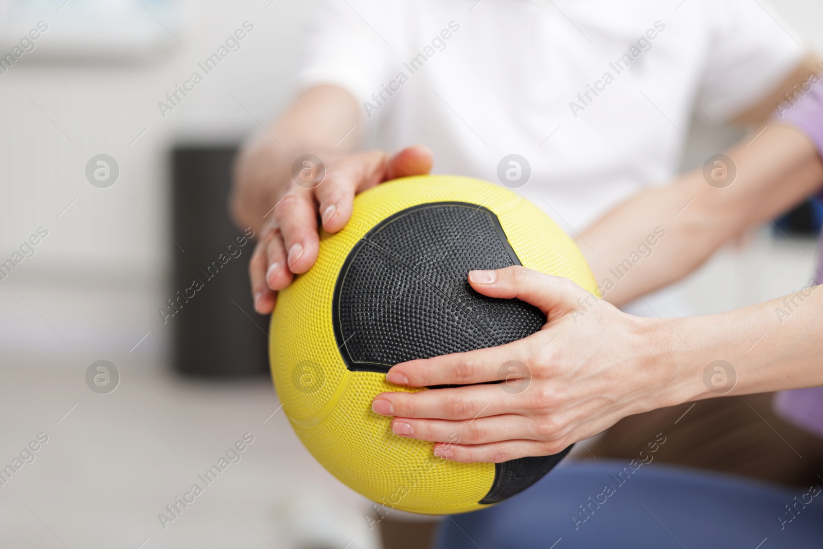 Doctor and patient exercising with medicine ball in clinic, closeup Photo of Doctor and patient exercising with medicine ball in clinic, closeup