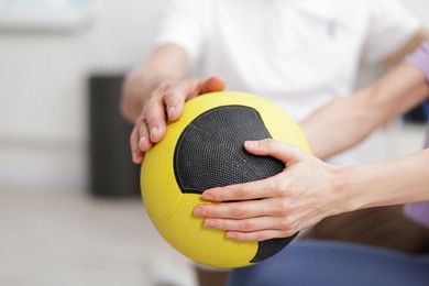 Photo of Doctor and patient exercising with medicine ball in clinic, closeup