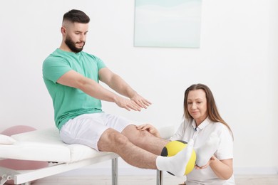 Photo of Doctor and patient exercising with medicine ball in clinic