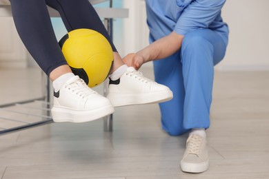 Photo of Doctor and patient exercising with medicine ball in clinic, closeup