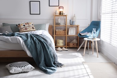 Photo of Cozy bed with soft linens, furniture and decor in stylish room. Home textile
