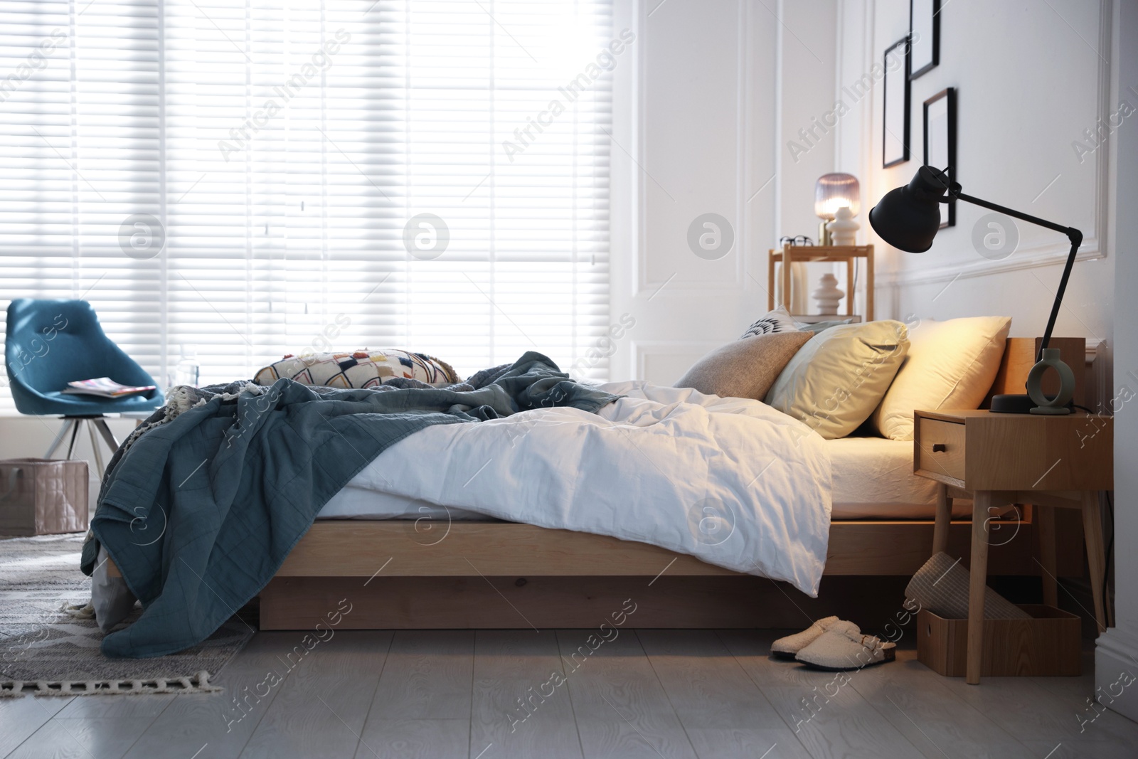 Cozy bed with soft linens, nightstand and lamp in stylish room. Home textile Photo of Cozy bed with soft linens, nightstand and lamp in stylish room. Home textile