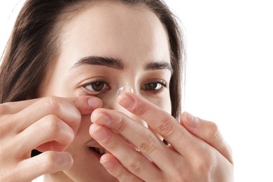 Photo of Woman putting in contact lens on white background, closeup