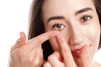 Photo of Woman putting in contact lens on white background, closeup