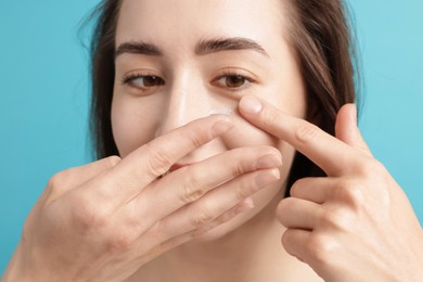 Photo of Woman putting in contact lens on light blue background, closeup