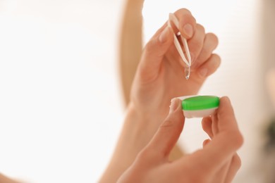 Photo of Woman taking contact lens out of case indoors, closeup. Space for text