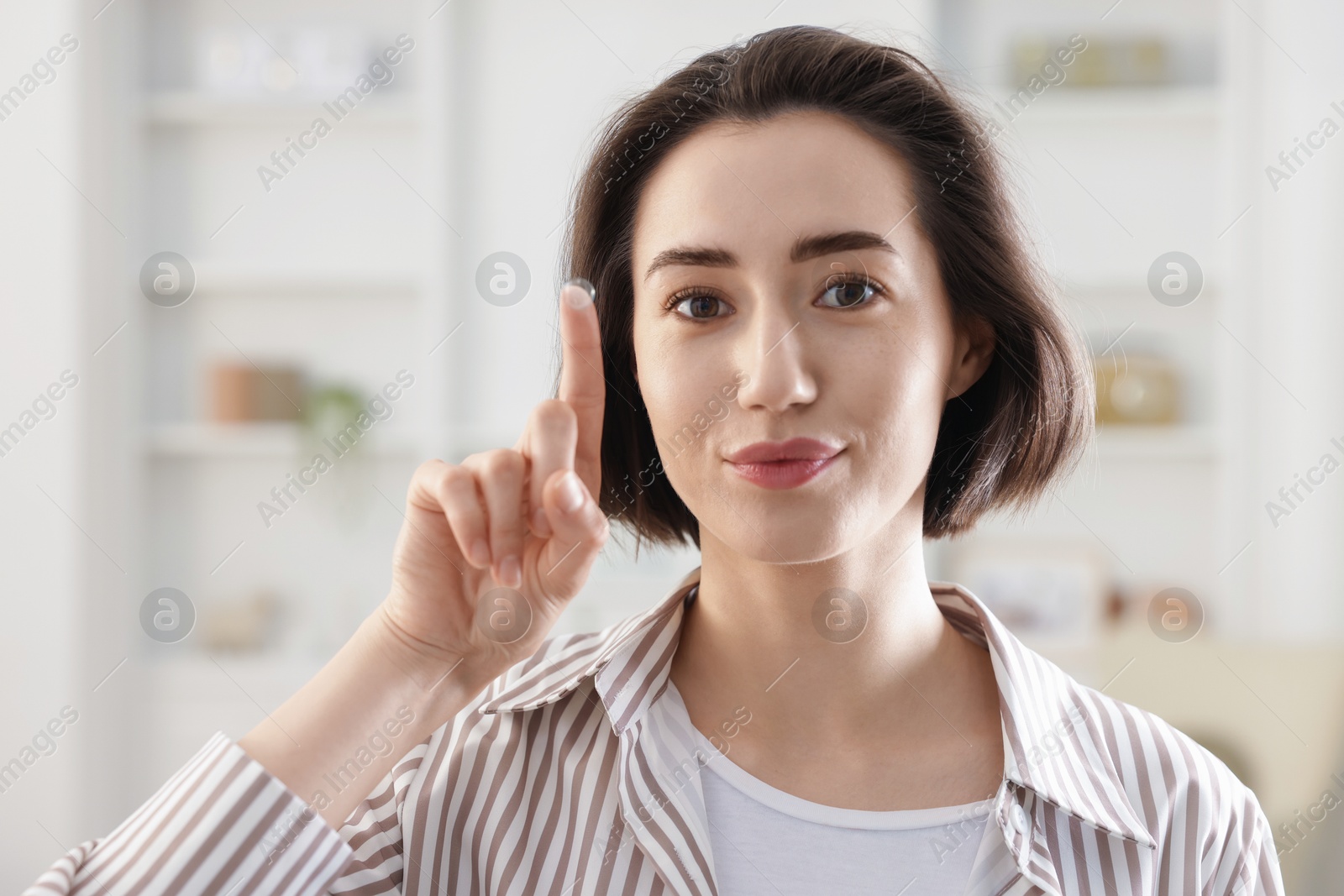 Happy woman with contact lens on her finger indoors Photo of Happy woman with contact lens on her finger indoors