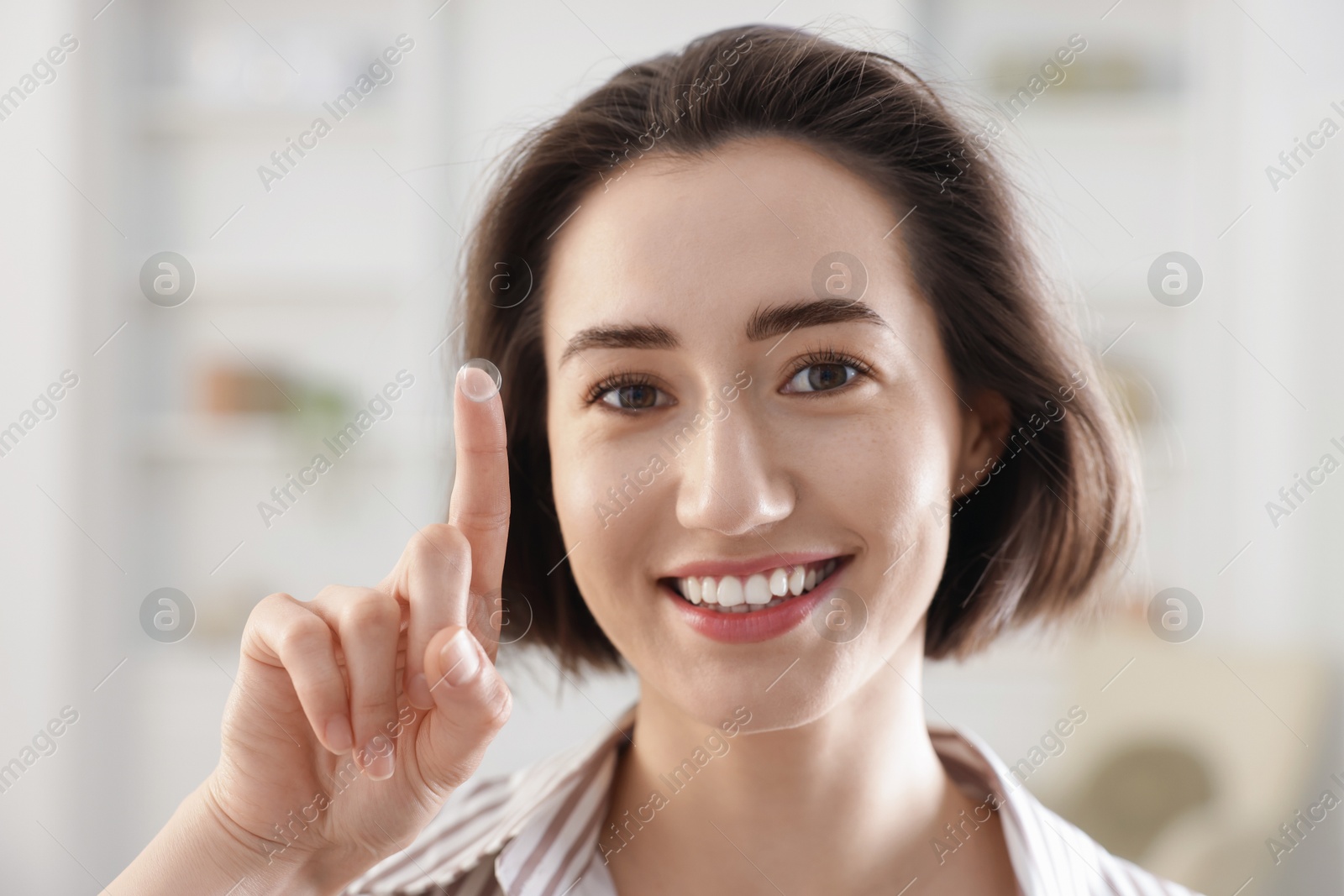 Happy woman with contact lens on her finger indoors Photo of Happy woman with contact lens on her finger indoors