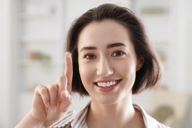 Photo of Happy woman with contact lens on her finger indoors