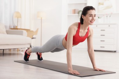 Photo of Woman doing plank exercise at home. Sport and healthy lifestyle