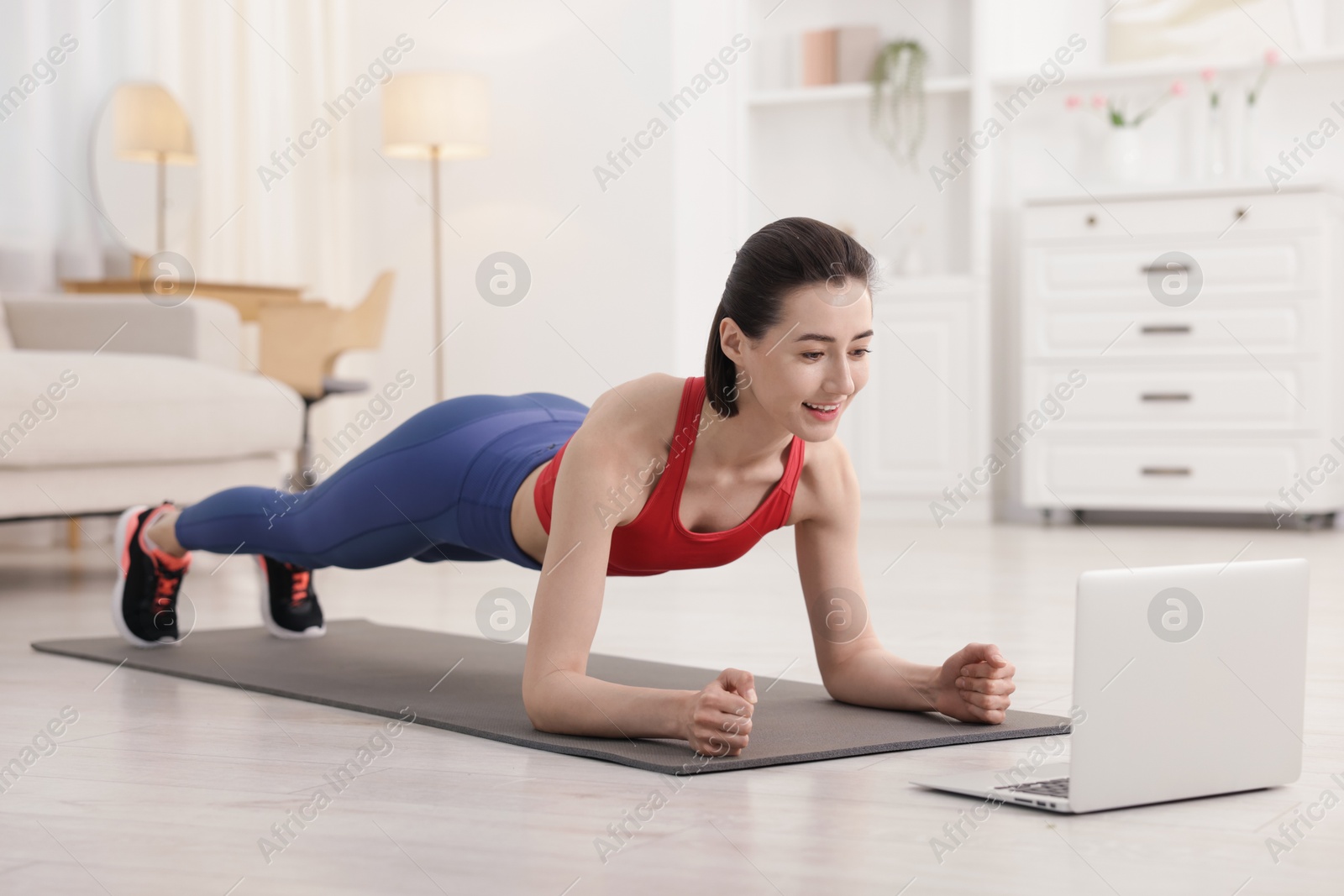 Woman doing plank exercise during online class with coach at home. Sport and healthy lifestyle Photo of Woman doing plank exercise during online class with coach at home. Sport and healthy lifestyle