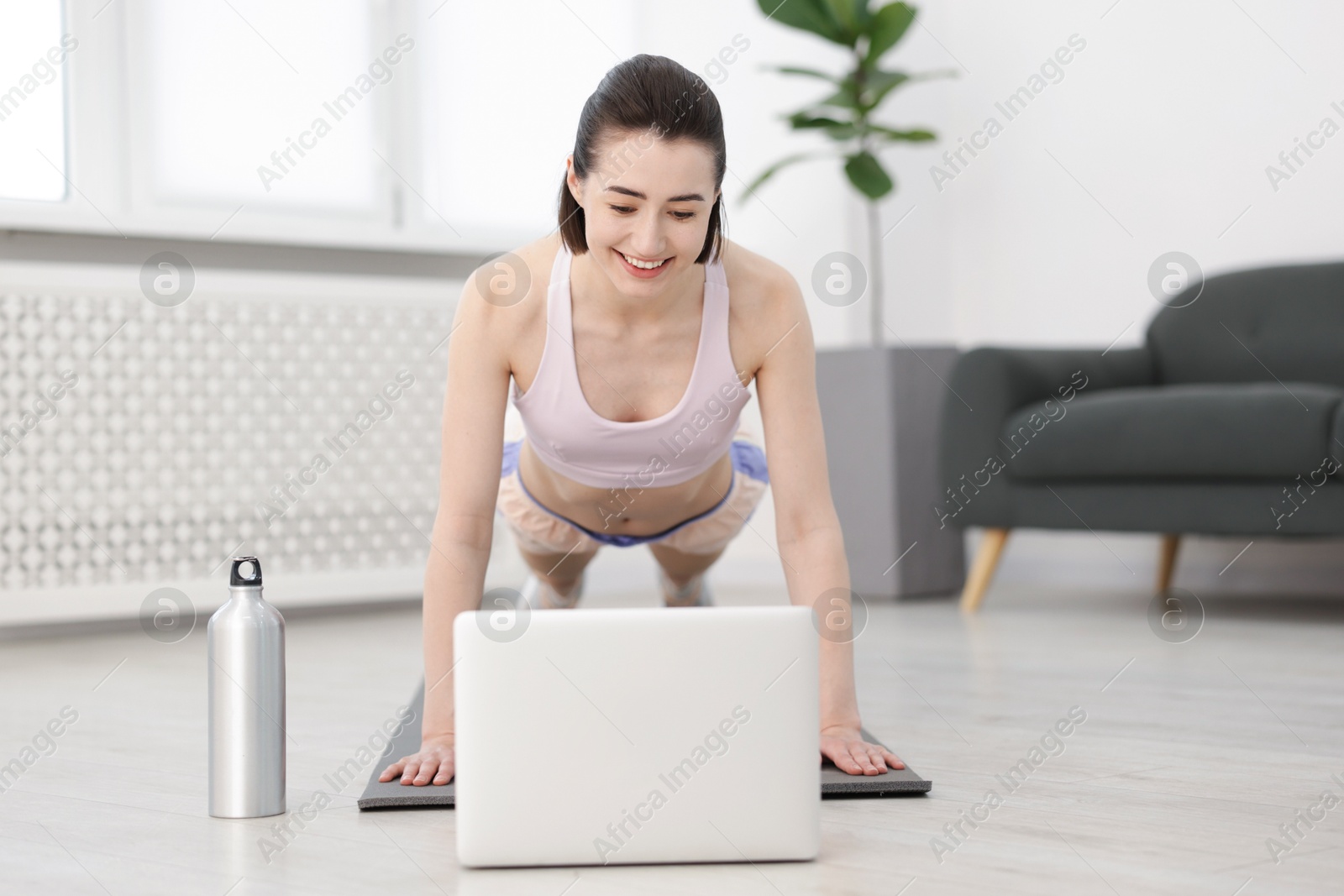 Woman doing plank exercise during online class with coach at home. Sport and healthy lifestyle Photo of Woman doing plank exercise during online class with coach at home. Sport and healthy lifestyle