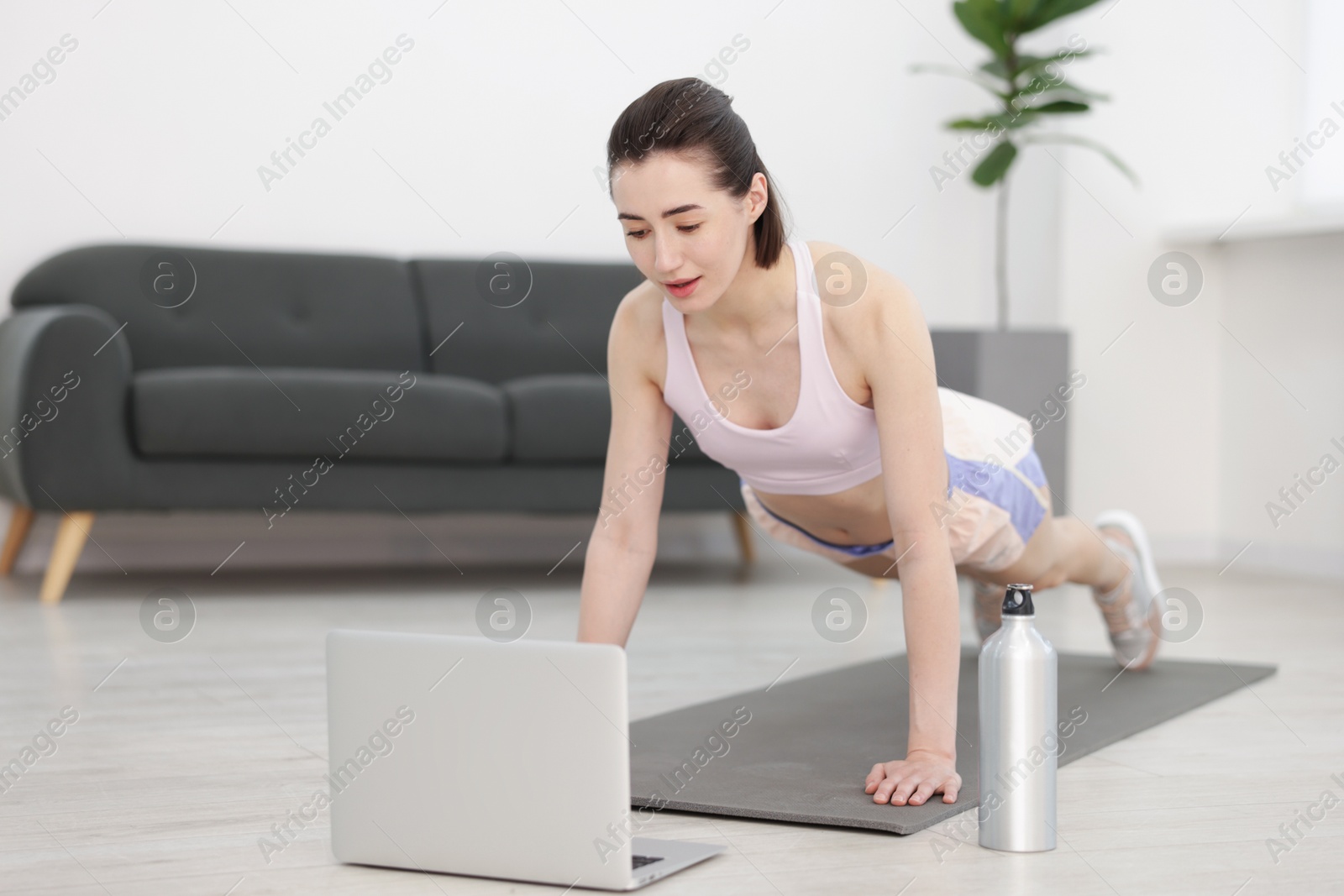 Woman doing plank exercise during online class with coach at home. Sport and healthy lifestyle Photo of Woman doing plank exercise during online class with coach at home. Sport and healthy lifestyle