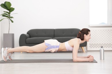 Photo of Woman doing plank exercise at home. Sport and healthy lifestyle
