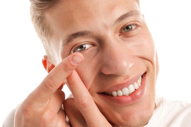 Photo of Man putting in contact lens on white background, closeup