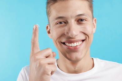 Photo of Man with contact lens on light blue background, closeup