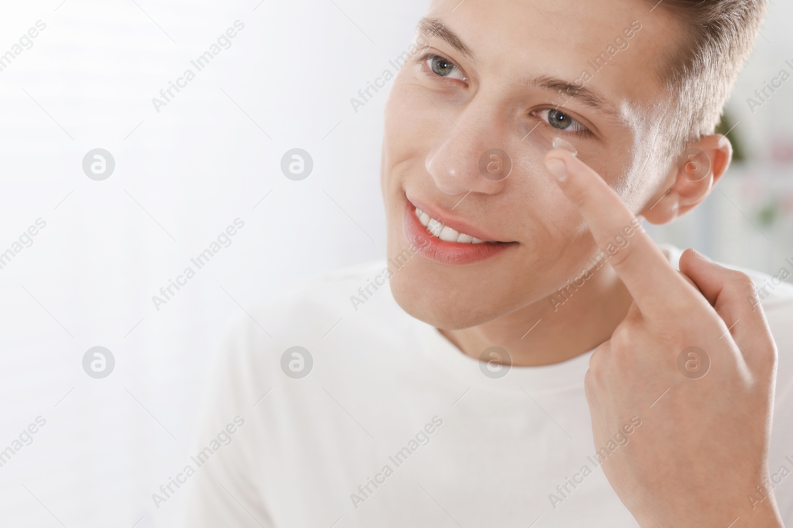 Man putting in contact lens at home, closeup. Space for text Photo of Man putting in contact lens at home, closeup. Space for text