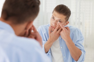 Photo of Man putting in contact lens near mirror at home