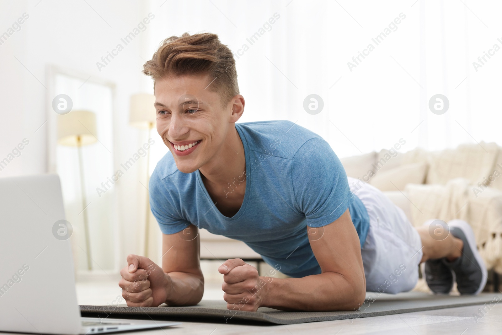 Man doing plank exercise during online class with coach at home. Sport and healthy lifestyle Photo of Man doing plank exercise during online class with coach at home. Sport and healthy lifestyle