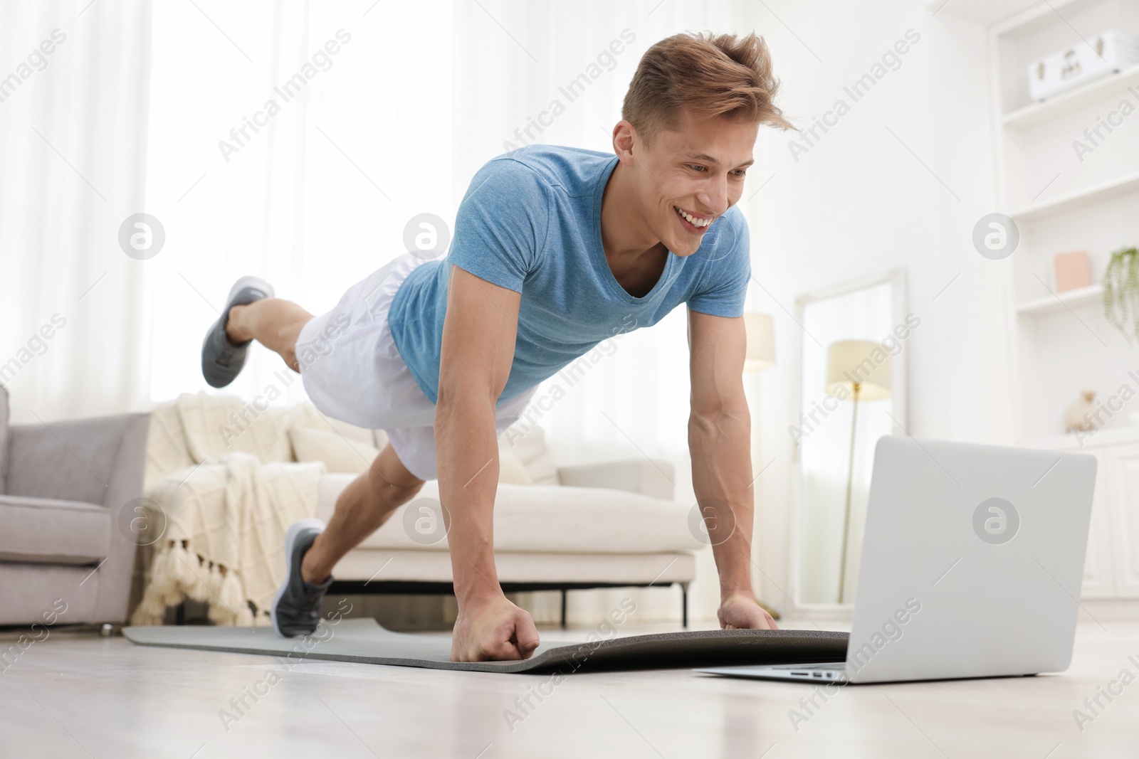 Man doing plank exercise during online class with coach at home. Sport and healthy lifestyle Photo of Man doing plank exercise during online class with coach at home. Sport and healthy lifestyle
