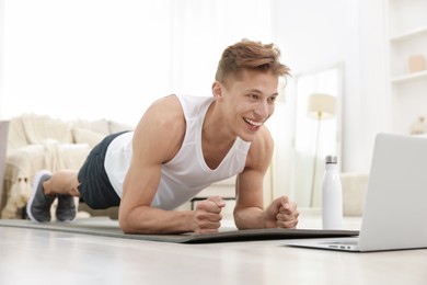 Photo of Man doing plank exercise during online class with coach at home. Sport and healthy lifestyle