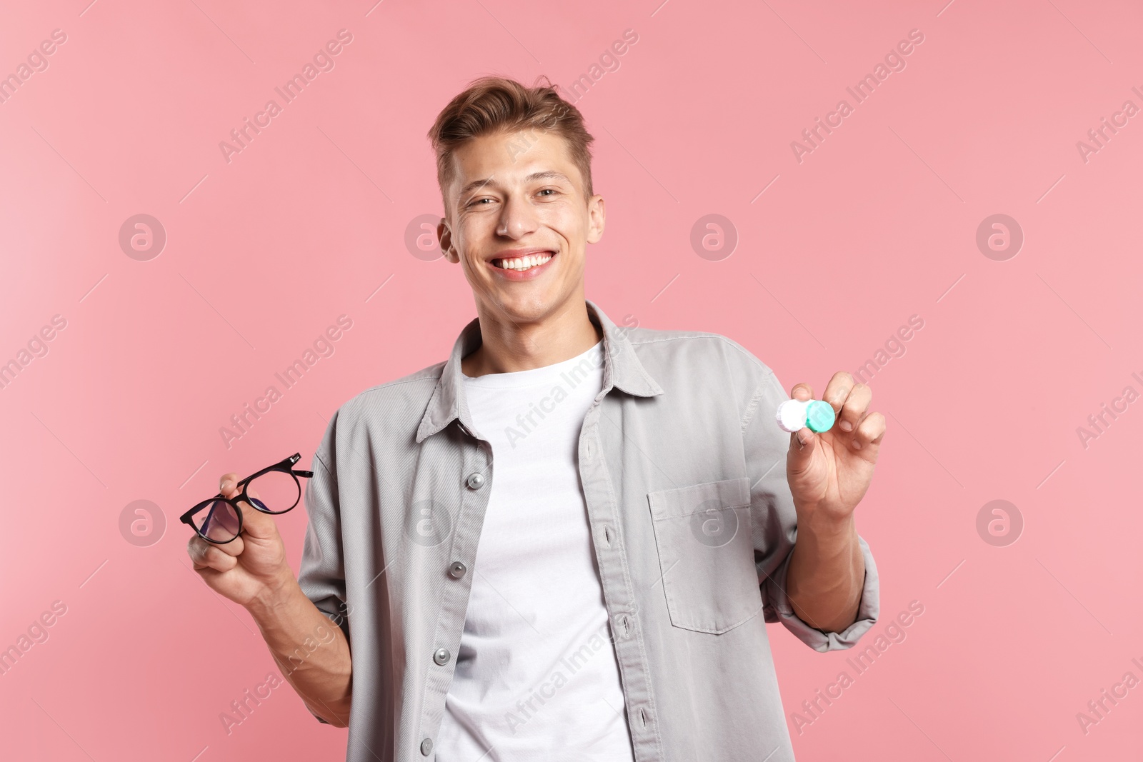 Man choosing between glasses and contact lenses on pink background Photo of Man choosing between glasses and contact lenses on pink background