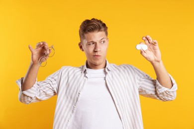 Photo of Man choosing between glasses and contact lenses on yellow background