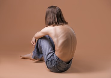 Photo of Woman suffering from anorexia on dark beige background