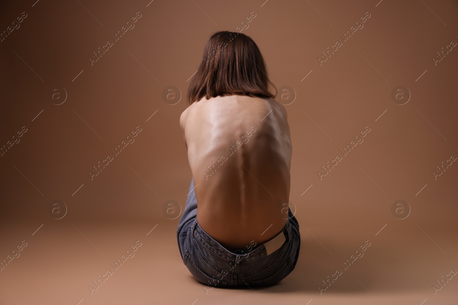 Woman suffering from anorexia on dark beige background, back view Photo of Woman suffering from anorexia on dark beige background, back view
