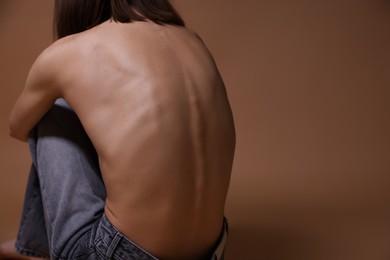 Photo of Woman suffering from anorexia on dark beige background, closeup. Space for text