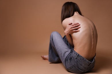Photo of Woman suffering from anorexia on dark beige background, back view. Space for text