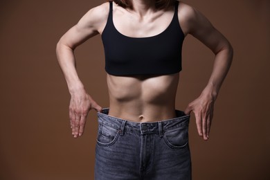 Photo of Woman suffering from anorexia on brown background, closeup