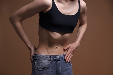 Photo of Woman suffering from anorexia on brown background, closeup