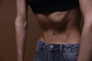 Photo of Woman suffering from anorexia on brown background, closeup