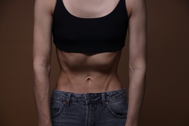 Photo of Woman suffering from anorexia on brown background, closeup