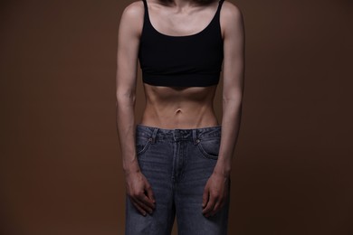 Photo of Woman suffering from anorexia on brown background, closeup