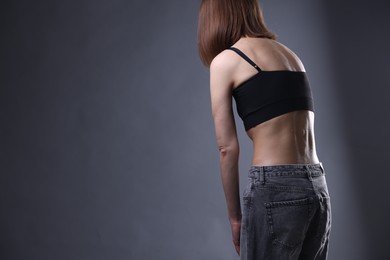 Photo of Woman suffering from anorexia on grey background, closeup. Space for text