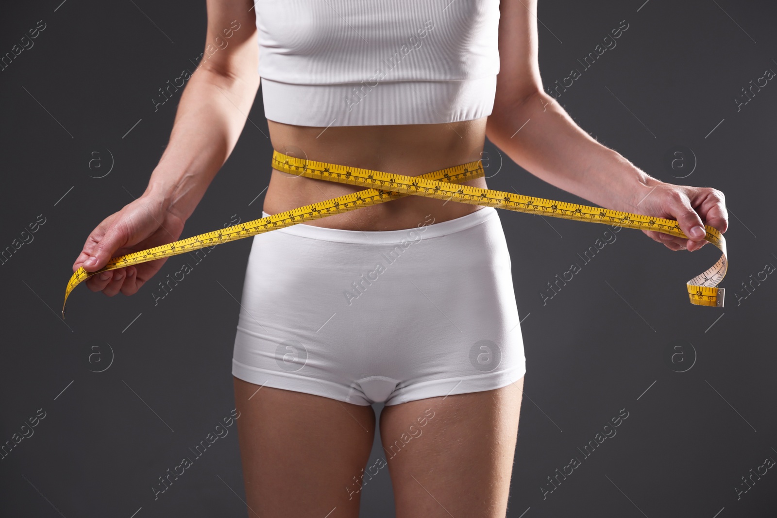 Anorexic woman measuring her waist on grey background, closeup Photo of Anorexic woman measuring her waist on grey background, closeup