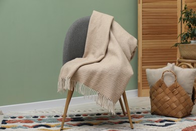 Photo of Comfortable armchair with woolen blanket and pillows indoors