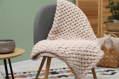 Photo of Comfortable armchair with woolen blanket and decor indoors