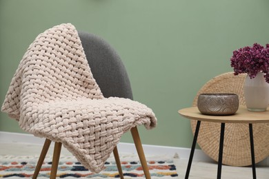 Photo of Comfortable armchair with woolen blanket and decor indoors